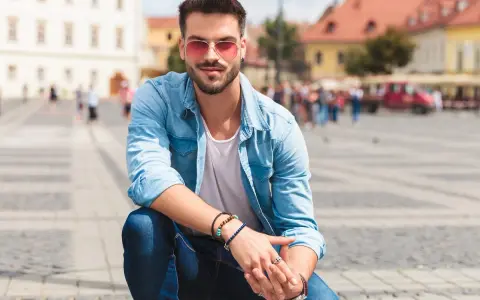 Uomo con occhiali da sole rosa e camicia di jeans, un'idea su come vestirsi in primavera uomo.