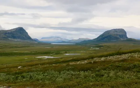 Vast, green valley with mountains and lakes, perfect for hiking trails Sweden.