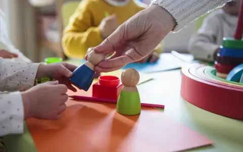 Dzieci bawią się drewnianymi ludzikami. W żłobku od jakiego wieku można zapisać dziecko?