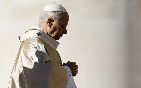 Papież w białej piusce i złotej szacie modli się, wierzę w boga. W jego oczach widać głęboką wiarę.