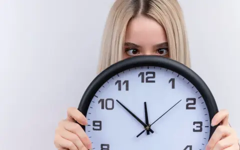 Dziewczyna z blond włosami ukrywa się za zegarem, patrząc zza niego. Czyżby czas miał dla niej jakieś szczególne 2233 znaczenie?