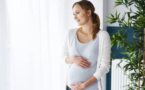 Kobieta w ciąży, która martwi się co na ból zęba w ciąży, delikatnie dotyka brzucha.