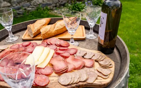 Plateau de charcuterie et fromage, pain frais, verres et bouteille de vin, une spécialité culinaire des Pyrénées.