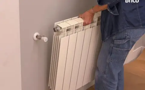 Persona quitando radiadores para pintar la pared.