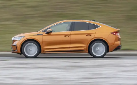 Pomarańczowy elektryczny SUV coupe w ruchu, widok z boku.