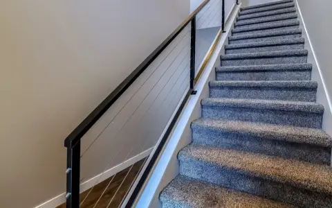 Miękka wykładzina na schody betonowe zapewnia komfort i bezpieczeństwo. Nowoczesna balustrada z linkami dodaje elegancji.