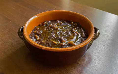 Una ciotola di terracotta con un saporito piatto di pasta e lenticchie, condito con olio d'oliva.