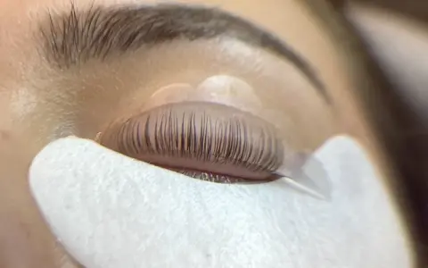 Un œil fermé, les cils recourbés sur un pad, prêts pour un allongement.