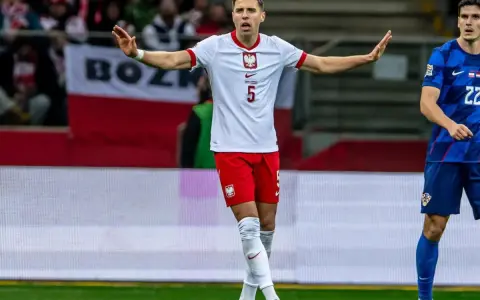 Piłkarz w białej koszulce z orłem, numer 5. Jan Bednarek po kontuzji wraca do gry, gestem prosi o spokój.
