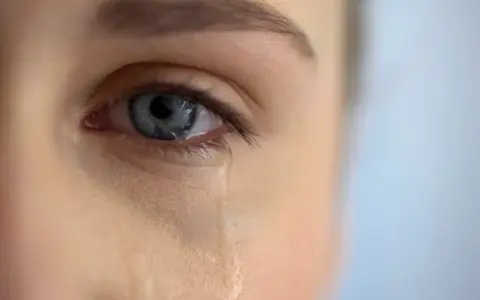 Zbliżenie na niebieskie oko, z którego spływa łza. Scena jak z filmu łzowego, pełna emocji.
