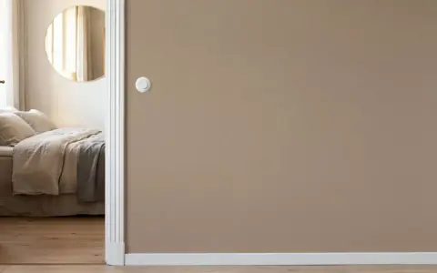 Camera da letto con letto accogliente, specchio rotondo e pareti color taupe.