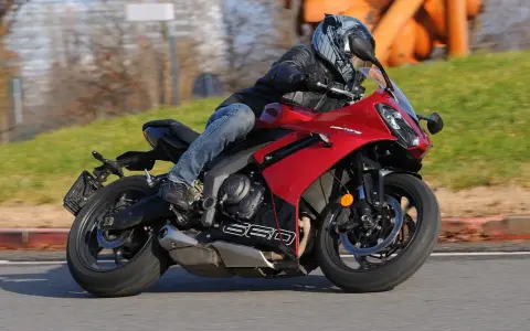 Un motociclista sfreccia su una moto sportiva rossa, tra le migliori moto sportive, con un casco moderno e jeans.