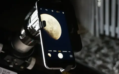 Mit dem Handy den Mond fotografieren: Ein Smartphone ist über einen Adapter an einem Teleskop befestigt, um den Mond abzulichten.