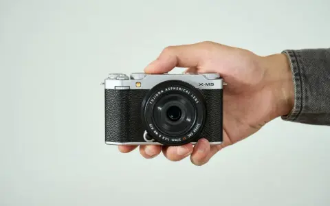 Mano sujetando una cámara Fujifilm X-M5 plateada y negra, lista para capturar momentos.