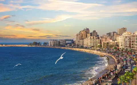 Il porto di Alessandria d'Egitto, con la sua vivace Corniche al tramonto, le onde del Mediterraneo e i gabbiani in volo.