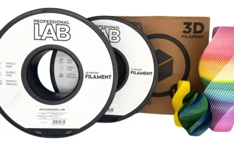 Dwie szpule filamentu jaki filament PLA marki Professional Lab, obok pudełka z napisem "3D FILAMENT" i kolorowych wydruków 3D.