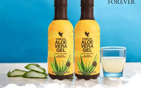 Dwa butelki napoju Forever Aloe Vera Gel, z widocznymi plastrami aloesu i szklanką napoju. Odkryj aloes właściwości.