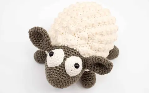 Oveja amigurumi de ganchillo con lana crema y marrón, ojos grandes y expresivos, lista para abrazar.