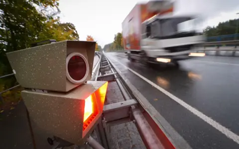 Blitzlicht erhellt die nasse Fahrbahn. Ein LKW rast vorbei. Das Zeugnisverweigerungsrecht bei Blitzern ist ein Thema für Fahrer.