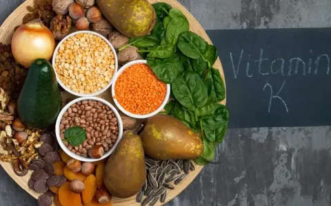 En bricka med mat rik på vitamin K1: spenat, päron, avokado, nötter, linser, bönor, torkade aprikoser, solrosfrön och choklad.