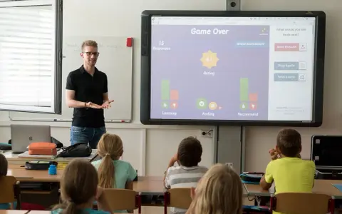 Lehrer präsentiert interaktive Spiele für Vertretungsstunden. Die Klasse spielt ein Quiz, das "Game Over" anzeigt.