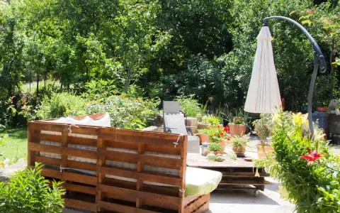 Un rincón acogedor en el jardín, con muebles de palets y plantas exuberantes. Ideal para una zona chill out.