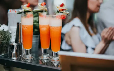 Orzeźwiający drink dla kobiet, ozdobiony owocami i listkami, gotowy do podania na letnim przyjęciu.