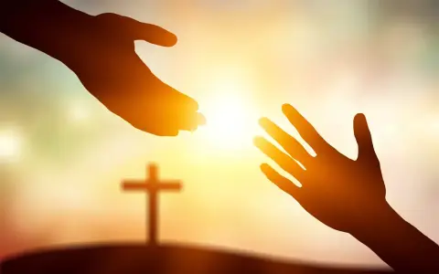 Zwei Hände reichen sich im warmen Licht entgegen, ein Kreuz im Hintergrund symbolisiert die Hilfe von Jesus Christus.