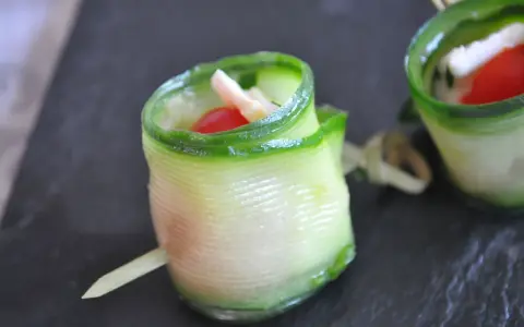 Délicieux wrap apéro de concombre garni de fromage frais, tomate cerise et herbes. Parfait pour un apéritif léger et coloré.