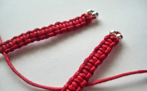 Czerwony splot shamballa z metalowymi koralikami, jak wygląda zbliżenie.
