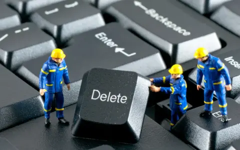 Figurki robotników w niebieskich kombinezonach próbują usunąć klawisz "Delete" z klawiatury. Działają jak incogni, usuwając niechciane dane.