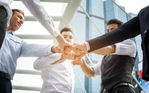 Un gruppo di uomini d'affari unisce i pugni, mostrando le loro caratteristiche personali di unità e determinazione.