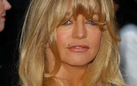 Goldie Hawn ler mot kameran, hennes blonda hår faller runt ansiktet. Tänker på alla roliga filmer med Goldie Hawn.