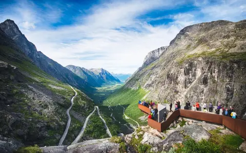 Besökare njuter av den dramatiska utsikten över Trollstigen i Åre, med en slingrande väg genom en grönskande dal.