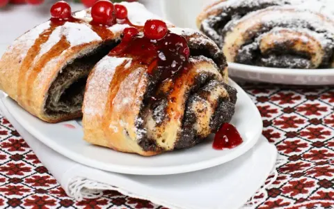 Saftige Mohnschnecken, verziert mit Kirschen und Puderzucker. Ein Genuss, der an die süßen Momente einer Schwangerschaft erinnert.