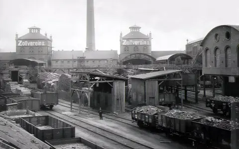 Ein Zeugnis der **hochindustrialisierung**: Zollverein II mit Schornstein, Loren voller Kohle und Holzlager.