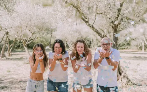 Photographie lifestyle : une famille lance des confettis sous des arbres fleuris, un moment de joie capturé.