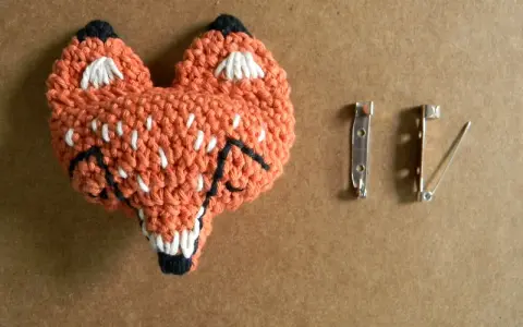 Un adorable zorro naranja tejido a crochet, listo para convertirse en un broche. ¡Perfecto para quienes buscan patrones de broches crochet únicos!