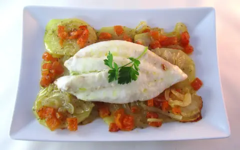 Filete de pescado blanco sobre patatas y zanahorias asadas, un delicioso gallo al horno.