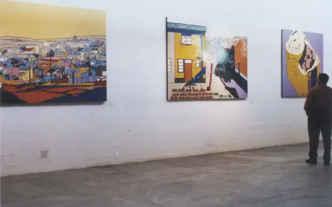 A person contemplates vibrant, stylized paintings in an art gallery, each piece curating meaning through bold colors and urban landscapes.