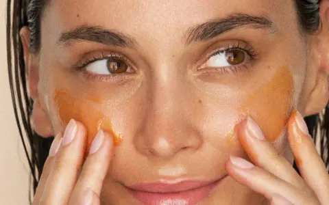Application d'un masque aloe vera visage. La peau est hydratée et lumineuse, les doigts massent doucement le produit.