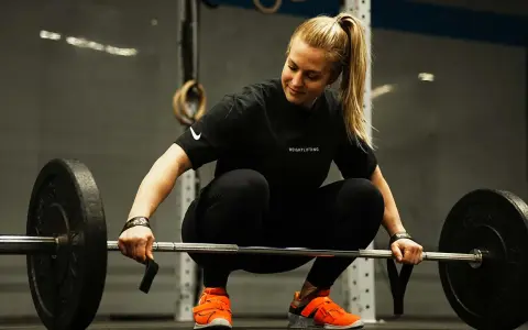Eine Frau in Sportkleidung bereitet sich auf das Gewichtheben vor. Eine **1 Woche Trainingspause sinnvoll** für Regeneration und neue Kraft.