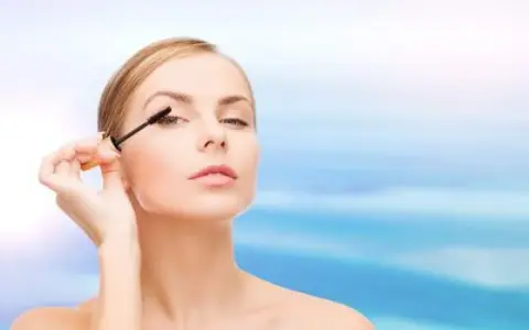 Une femme applique du mascara sur ses cils. Apprendre comment mettre du mascara pour un regard intense.