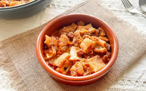 Un cuenco de barro con callos a la vizcaina, un plato tradicional español lleno de sabor y textura.