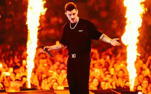 Artysta na scenie, otoczony płomieniami, śpiewa dla tłumu. To będzie gorący rok dla mrozu koncerty 2026!