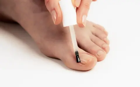 Application d'un soin transparent sur un ongle abîmé pour le protéger et le renforcer.