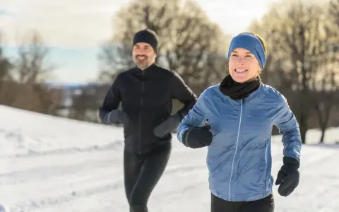 Ein Paar genießt das Laufen im Winter. Sie tragen passende Winterkleidung, um sich warm zu halten.