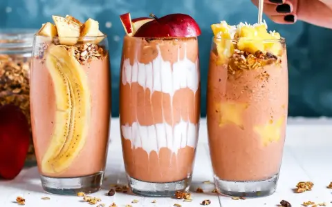 Drei leckere, bunte Smoothies im Glas, garniert mit Früchten und Müsli. Perfekt für den gesunden **Aufbau-Shake** am Morgen.