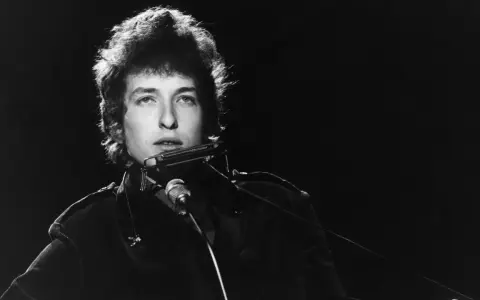 Bob Dylan spielt Mundharmonika, ein wahrer "rolling stone" auf der Bühne, mit seinem charakteristischen Blick.