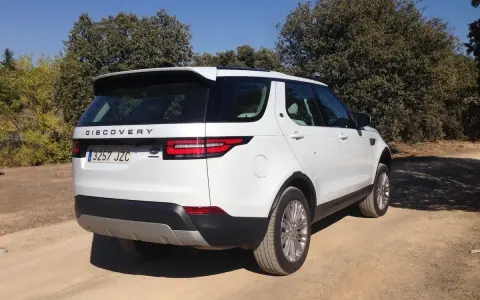Un Land Rover Discovery HSE blanco aparcado en un camino de tierra rodeado de árboles.